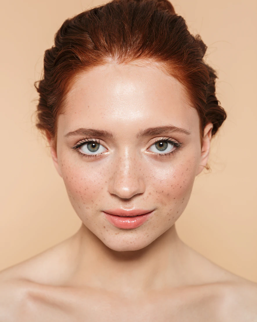Woman with freckles against a warm beige backdrop