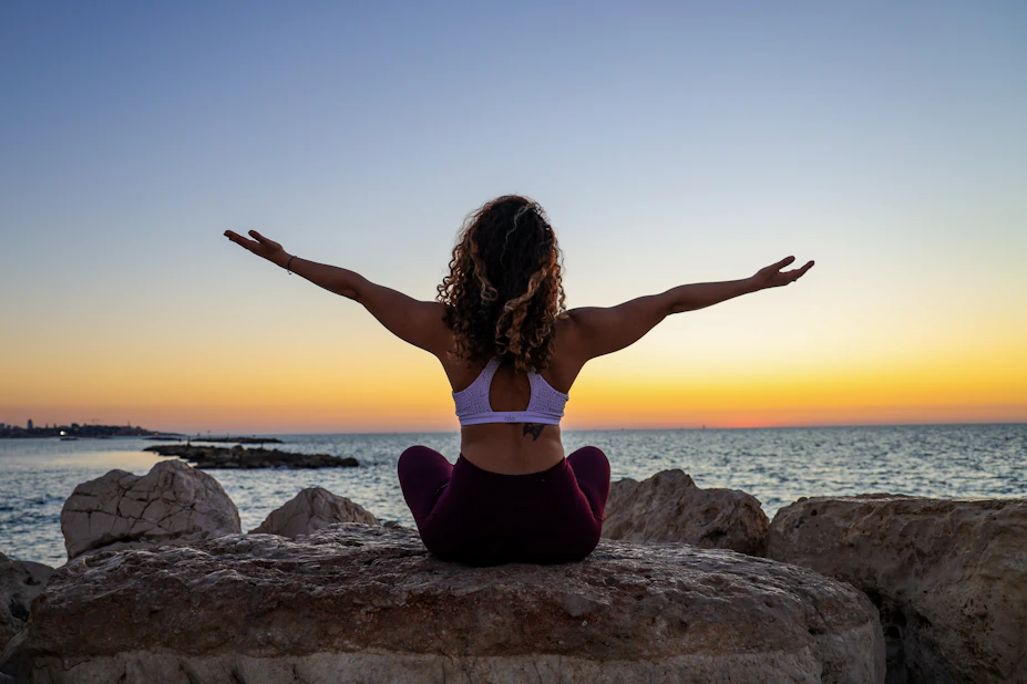 Woman sitting by the sea at sunset